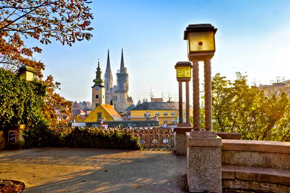 Na pierwszym planie kamienny taras i ozdobne, stare latarnie. W tle panorama Zagrzebia z Katedrą.